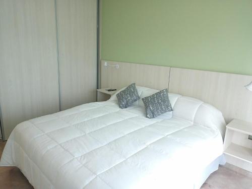 1 cama blanca con 2 almohadas en el dormitorio en MONTE HERMOSO 1DORM CENTRO, en Monte Hermoso