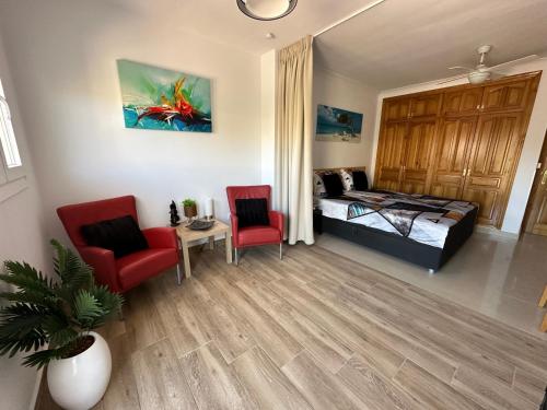 a bedroom with a bed and two red chairs at B&B Villa Archez in Árchez