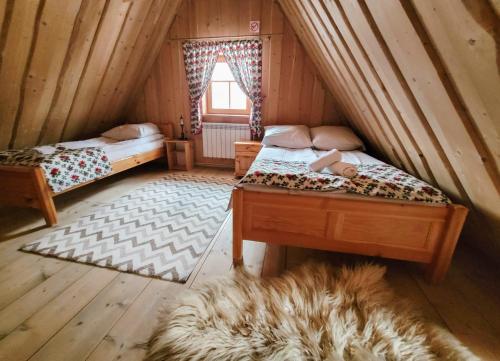 een zolderkamer met 2 bedden en een tapijt bij Domek góralski in Ciche Małe