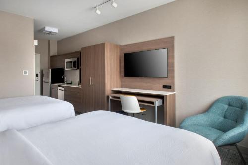 a hotel room with two beds and a desk and a tv at TownePlace Suites by Marriott New York Brooklyn in Brooklyn