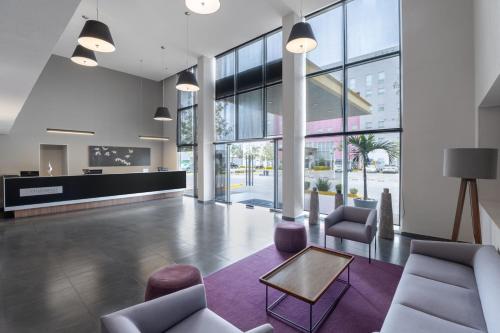 a lobby with chairs and a table and windows at City Express by Marriott Silao Aeropuerto in Silao