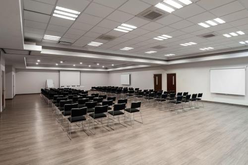 a large room with chairs and a white wall at City Express by Marriott Silao Aeropuerto in Silao
