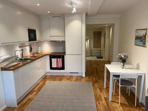 uma cozinha com armários brancos, uma mesa e uma sala de jantar em New apartment, perfect for exploring Stockholm em Lidingö