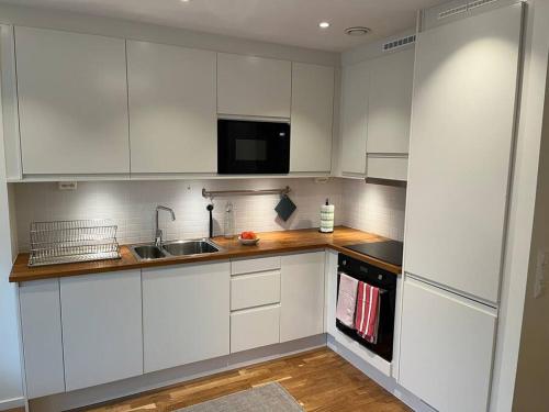 una cocina con armarios blancos y fregadero en New apartment, perfect for exploring Stockholm, en Lidingö