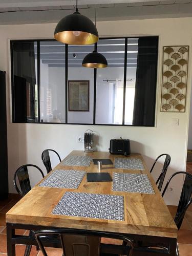 a wooden table with chairs in a room at Gîtes & Spa de charme " Ploum" in Pouydesseaux