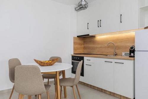 a kitchen with white cabinets and a table and chairs at MS Homes Peraia 1 in Perea