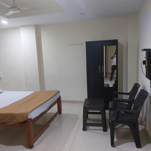 a bedroom with a bed and a chair and a person in the mirror at Swastik lodge in Belgaum