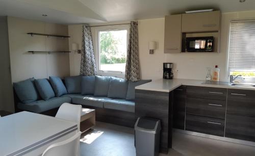 a living room with a blue couch and a kitchen at davorel mobil home in Les Mathes