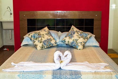 two towel swans making a heart on a bed at Pousada e restaurante Além das Nuvens in Guaratinguetá