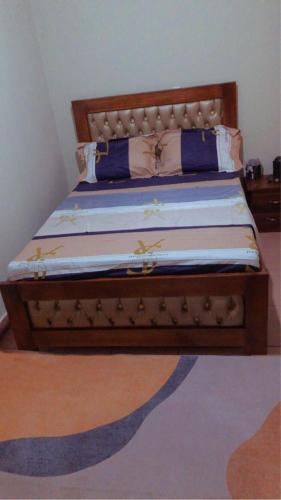 Una cama con marco de madera y almohadas azules. en Studio meublée 1 chambre Etoug ebe, en Yaoundé