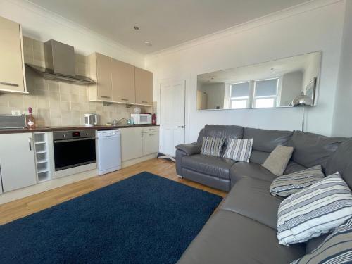 a living room with a couch and a kitchen at Millport Beach Apartment, Crichton St, sea views in Millport