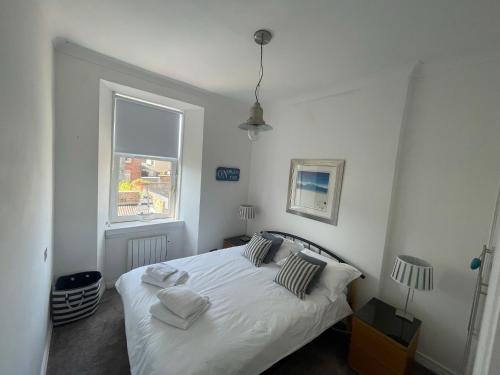 a bedroom with a white bed and a window at Millport Beach Apartment, Crichton St, sea views in Millport