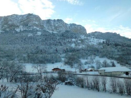 a snow covered hill with a house and mountains at Studio cabine au cœur de la montagne Les Memises in Thollon