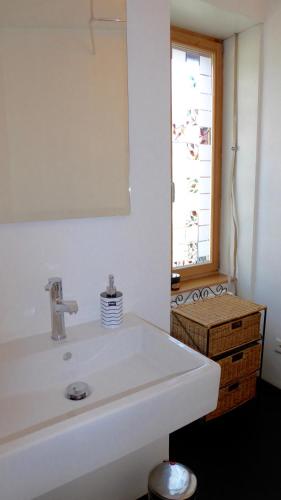 une salle de bain avec un lavabo blanc et une fenêtre dans l'établissement Georgian Guest Rooms, à Bâle
