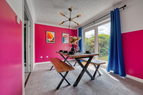 uma sala de jantar com uma mesa e uma parede rosa em Large 4 bedroom house - driveway - close to NEC! em Solihull