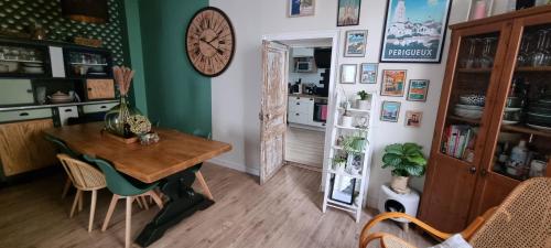 une salle à manger avec une table et une horloge au mur dans l'établissement Maison de centre ville, à Périgueux