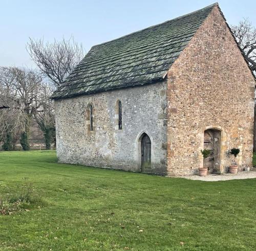 an old brick church with a grass field at The Studio in Climping in Climping