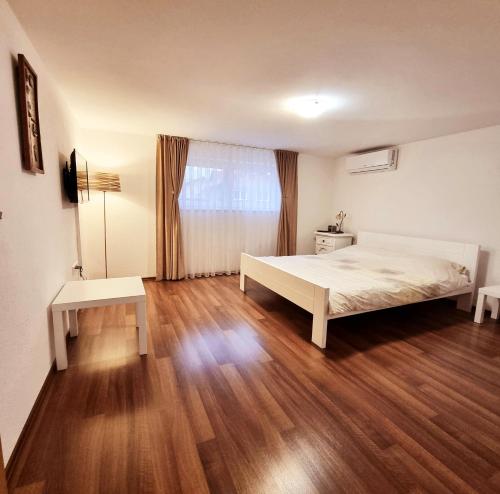 een slaapkamer met een bed en een houten vloer bij Apartment Kapetanovic in Bosanski Šamac