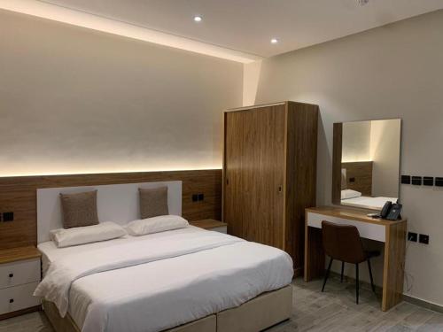 1 dormitorio con cama, escritorio y espejo en قمة راحتي للشقق المخدومة Qimat Rahaity SERVICED APARTMENTS, en Yanbu