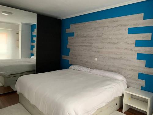 a bedroom with a white bed and blue walls at Apartamento en Liencres in Liencres