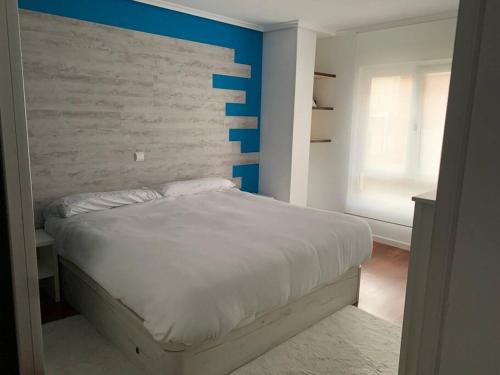 a bedroom with a white bed and a blue wall at Apartamento en Liencres in Liencres