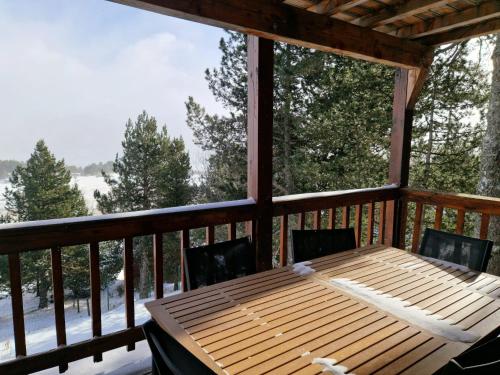 una mesa de madera en un porche cubierto con nieve en Chez Rémy, en Les Angles