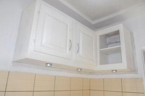 una cocina con armarios blancos en una habitación en Studio meublé à bas prix (salon, chambre, douche, cuisine), en Yasika