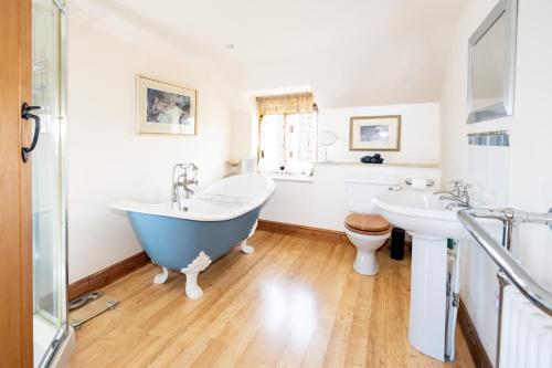 ein Badezimmer mit zwei Waschbecken, einer Badewanne und einem WC in der Unterkunft Characterful Cottage in Heart of Dorset in Buckland Newton