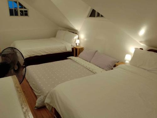 two beds in a small room with white sheets at The White Pine at No 7 Pucay Village in Baguio