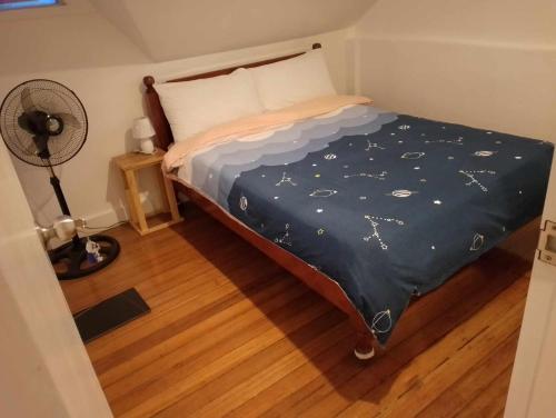 a bedroom with a bed with a blue comforter and a fan at Whyte Pyne Transient House in Baguio