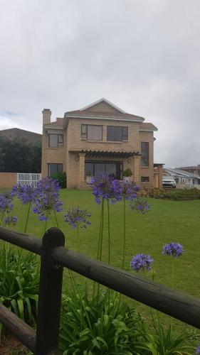 una casa con flores púrpuras delante de un patio en Die Melkhout Huis, en Reebok