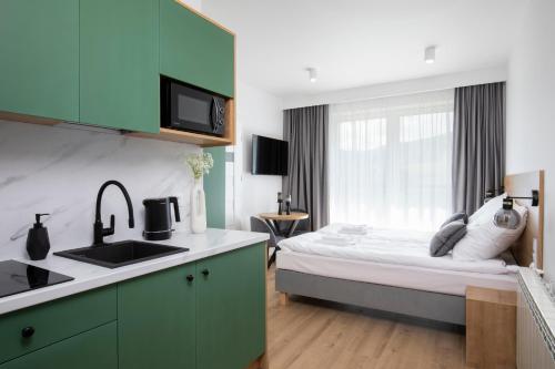 a bedroom with a bed and a kitchen with a sink at Villa Gorczański Zakątek in Konina