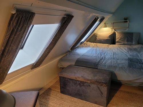 een kleine slaapkamer met een bed en 2 ramen bij BakeryInn Amersfoort in Amersfoort