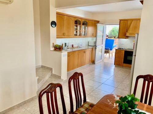 a kitchen with wooden cabinets and a table and chairs at KambiGardens in Chlorakas