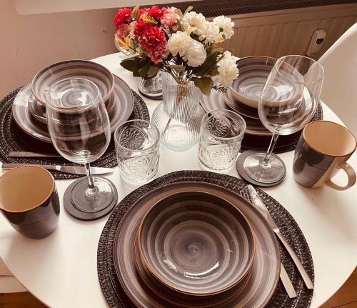 una mesa con platos y vasos y un jarrón con flores en Savón - City Apartment, en Bad Oeynhausen