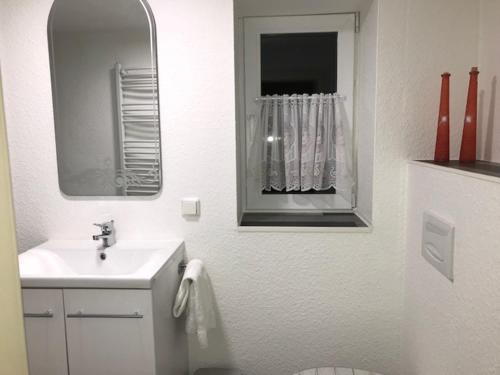 a white bathroom with a sink and a mirror at Gästehaus Reimold in Bebra