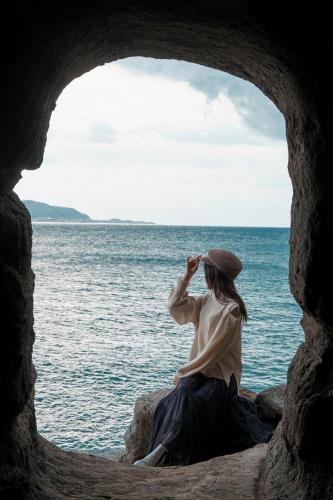 a woman sitting on a rock looking at the ocean at UMInoTERRACE in Minamiboso