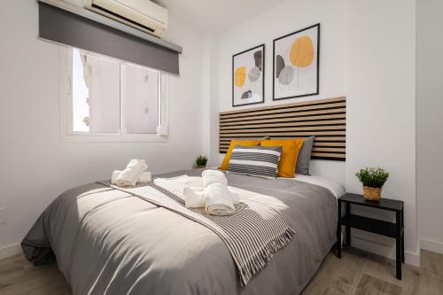 een slaapkamer met een groot bed met witte en oranje kussens bij Nordik Apartments Urban - Pedregalejo "Reine" in Málaga