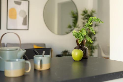 een zwarte tafel met een vaas met een plant en bekers bij Nordik Apartments Urban - Pedregalejo "Reine" in Málaga