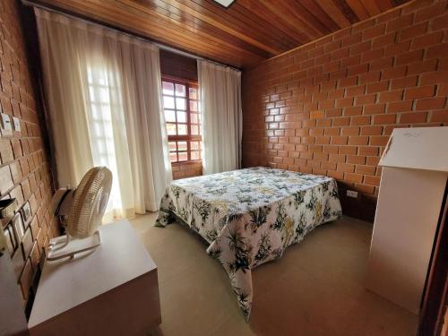 a bedroom with a bed and a brick wall at Casa de Campo Novo gravatá em condomínio, lazer completo com piscina compartilhada, churraqueira e forno a lenha privado e uma vista espetacular e com aquele friozinho in Gravatá