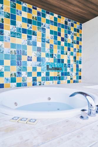 a bath tub in a bathroom with a tiled wall at UMInoTERRACE in Minamiboso