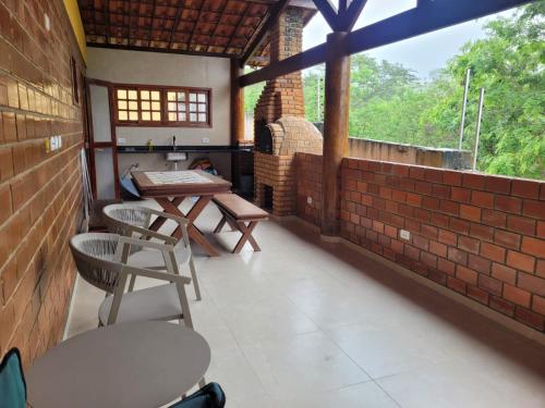 a patio with chairs and a table and a brick wall at Casa de Campo Novo gravatá em condomínio, lazer completo com piscina compartilhada, churraqueira e forno a lenha privado e uma vista espetacular e com aquele friozinho in Gravatá