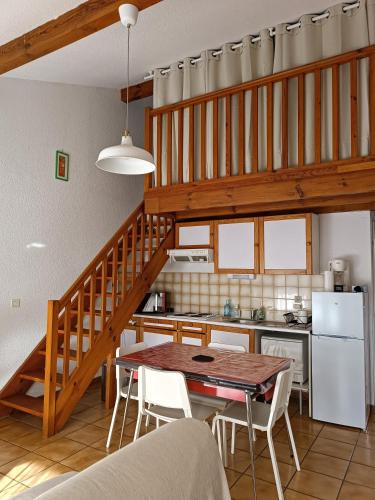 a kitchen with a table and a kitchen with a staircase at Maison classée avec jardinets à 800m de la plage in Capbreton