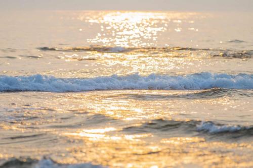 a beach with the sun shining on the water at UMInoTERRACE in Minamiboso