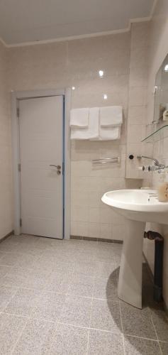 ein Badezimmer mit einem weißen Waschbecken und einer Tür mit Handtüchern in der Unterkunft Motel Monza in Blagoewgrad