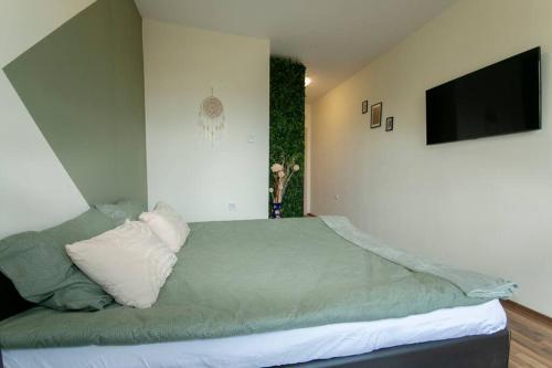 um quarto com uma cama verde e uma televisão de ecrã plano em Chic&Cozy Apartment in Nessebar em Nessebar