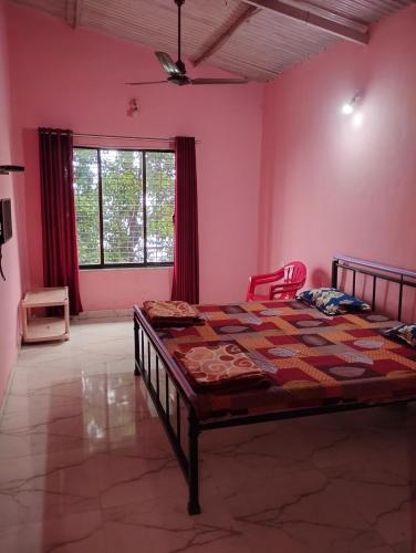 a bedroom with a bed in a room with pink walls at Laxmi Cottage in Matheran