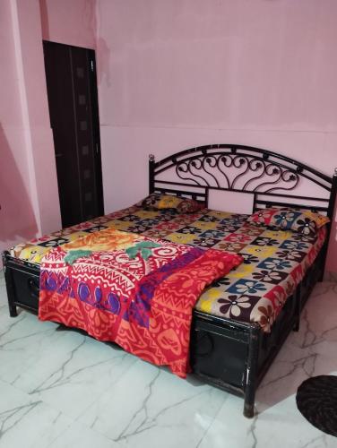 a bed in a pink room with a colorful bedspread at Laxmi Cottage in Matheran