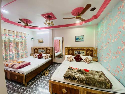 a bedroom with two beds and a ceiling fan at Shree Avantika home stay in Ujjain