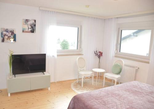 a bedroom with a flat screen tv and two chairs at Ferienhaus Julia - Ossiacher See in Sattendorf